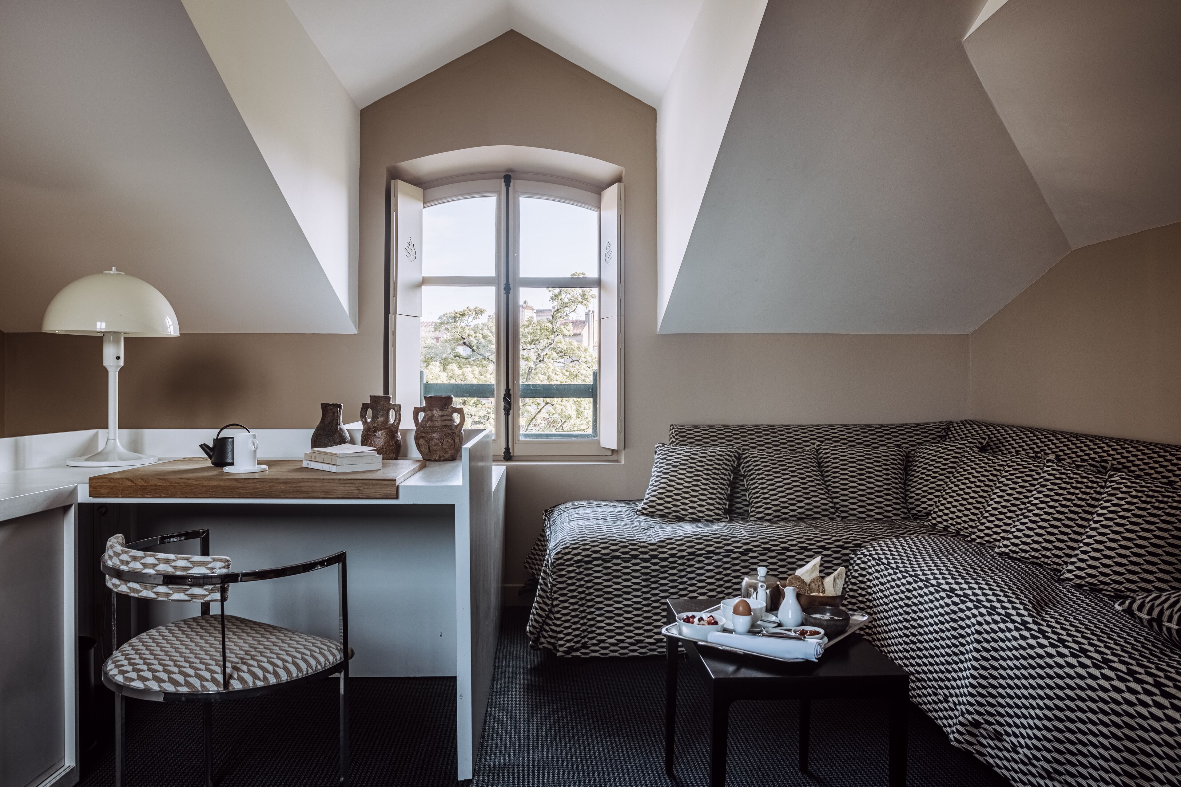Una habitación acogedora con escritorio, silla y sofá estampado.