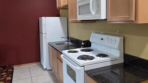 A kitchen with a white stove, microwave, and refrigerator. - SureStay Studio By Best Western El Dorado (El Dorado)
