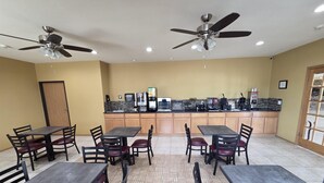 A spacious indoor dining area with multiple tables and chairs, ceiling fans, and a kitchen counter with various appliances. - SureStay Studio By Best Western El Dorado (El Dorado)