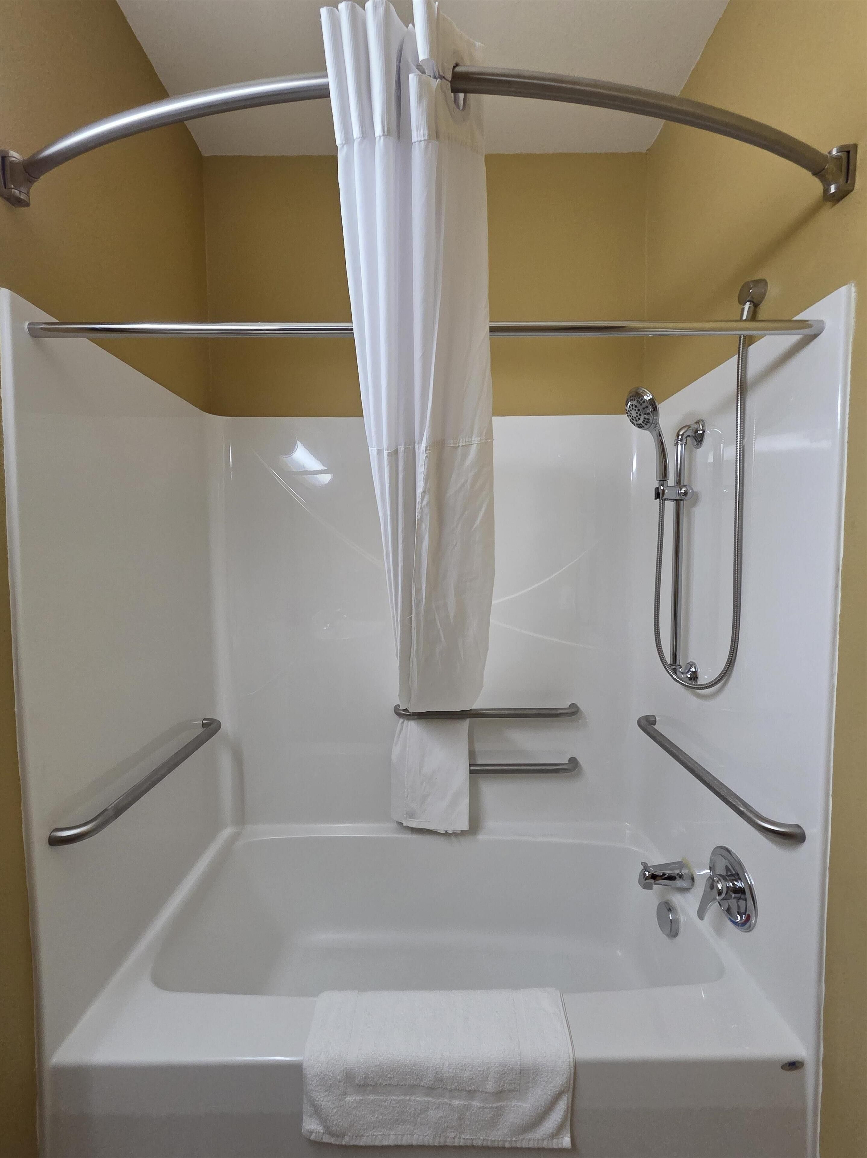 Une salle de bain équipée d’une baignoire, d’une douche et de barres d’appui.