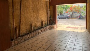 A hallway with a tiled floor, a wooden wall with vertical slats, and a stone border. - Hotel Papagayo (Veracruz)