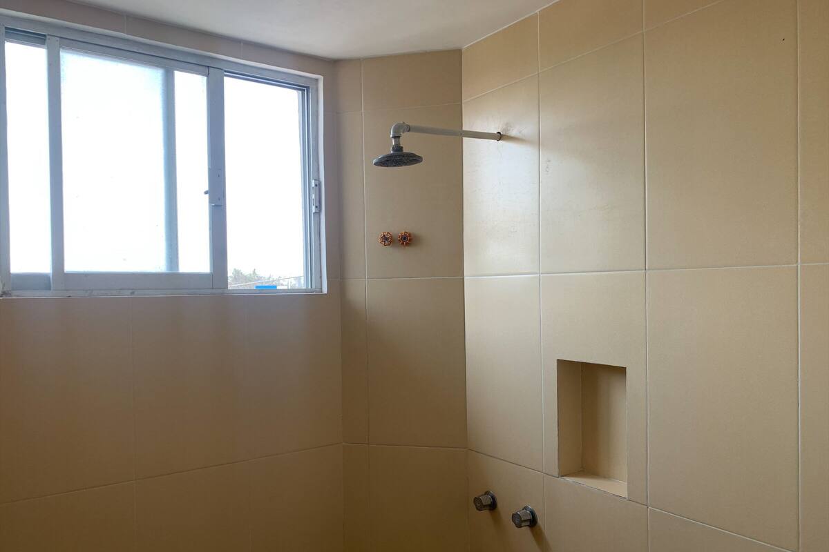 Ducha con ventana, perchero y una pequeña estantería.