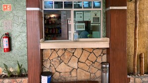 A reception area with a 'Recepción Bienvenidos' sign, a cash register, a fire extinguisher, and a trash bin. - Hotel Papagayo (Veracruz)
