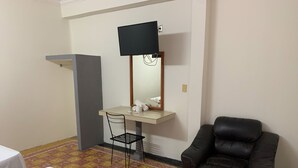 A hotel room with a bed, a desk with a chair, a leather armchair, and a television mounted on the wall. - Hotel Papagayo (Veracruz)