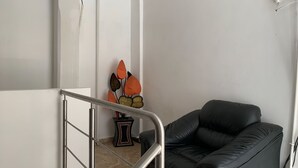 A staircase with a metal railing, a black leather sofa, and a decorative wall piece with orange and brown leaves. - Hotel Papagayo (Veracruz)