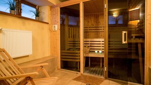 A wooden sauna with sliding glass doors, a bench, and a small table with a candle. - Hotel Solny (Wieliczka)