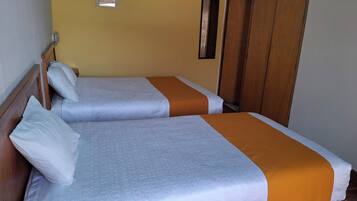 Quarto com duas camas, cabeceiras e guarda-roupa de madeira.
