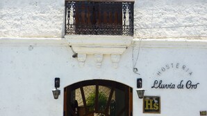 Un edificio con fachada blanca, un balcón con barandilla de hierro forjado y una entrada arqueada.