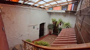Una escalera con barandillas ornamentadas, suelo a cuadros y plantas en macetas.