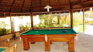 A pool table in a room with a thatched roof and large windows. - Pousada Corais do Sul (Tibau do Sul)