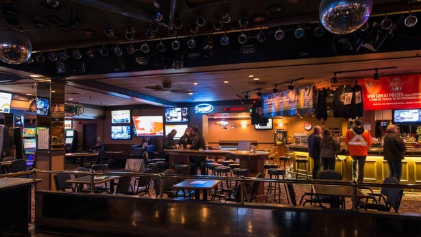 A bar with multiple screens, tables, and chairs. - Travelodge by Wyndham Winnipeg Airport West (Winnipeg)