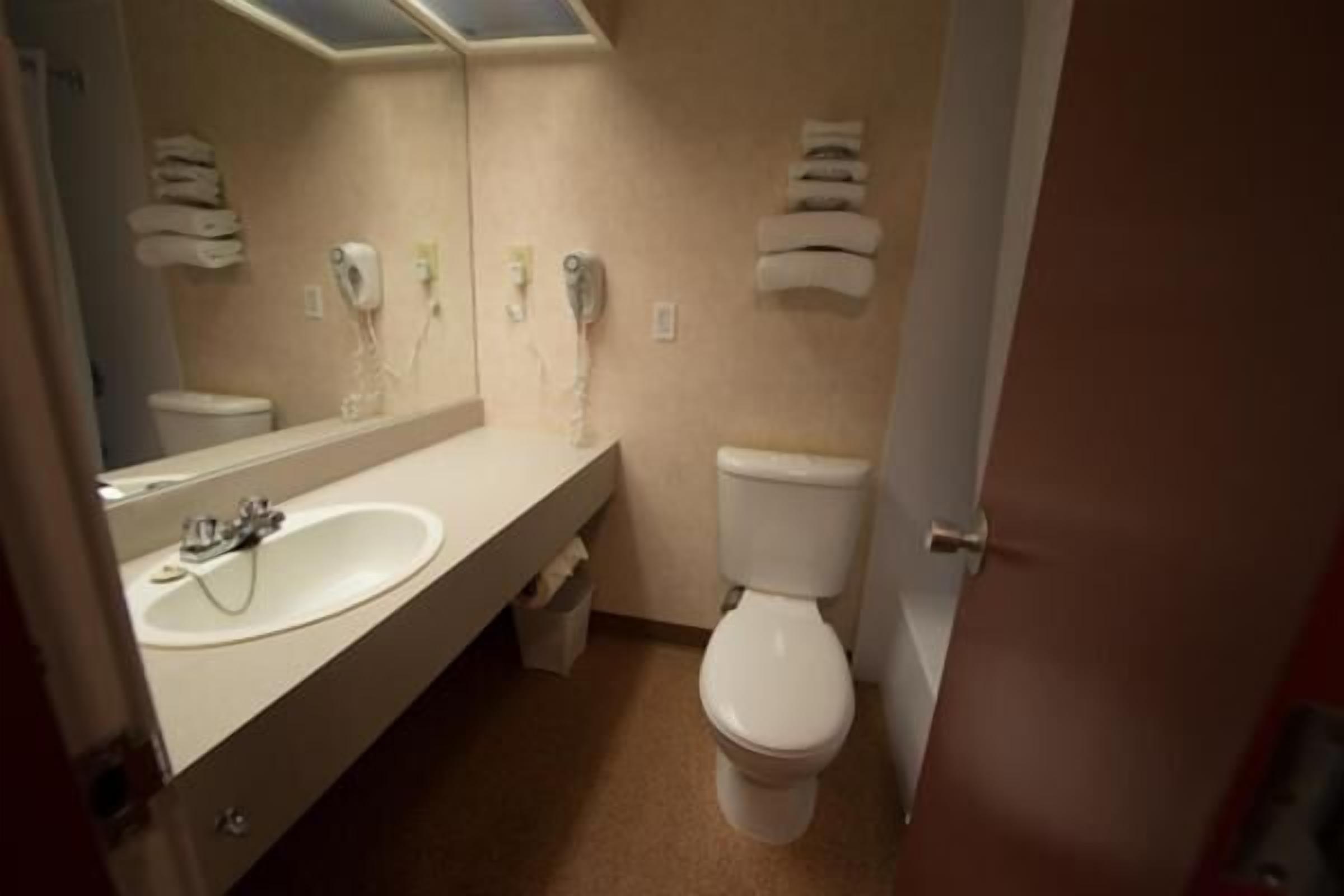 Een badkamer met een wastafel, spiegel, toilet en handdoekdispenser.