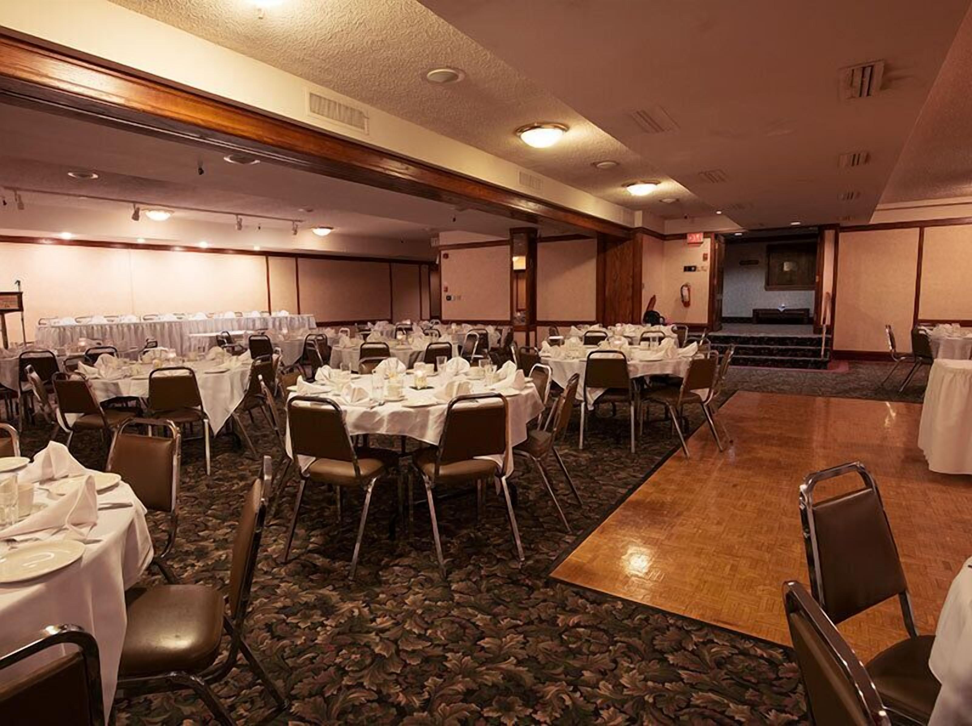 Une salle de banquet avec de nombreuses tables rondes disposées pour le repas, équipées de chaises et de couverts.