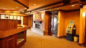 A hotel lobby with a check-in counter, a fireplace, and a self-service kiosk. - Travelodge by Wyndham Winnipeg Airport West (Winnipeg)