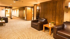 A hotel lobby with a checkered carpet, leather seating, a wooden reception desk, and a wooden wall. - Travelodge by Wyndham Winnipeg Airport West (Winnipeg)