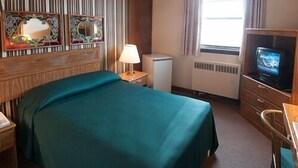 A hotel room with a bed, a desk, a television, and a mirror. - Curtis Gordon Motor Hotel (Winnipeg)