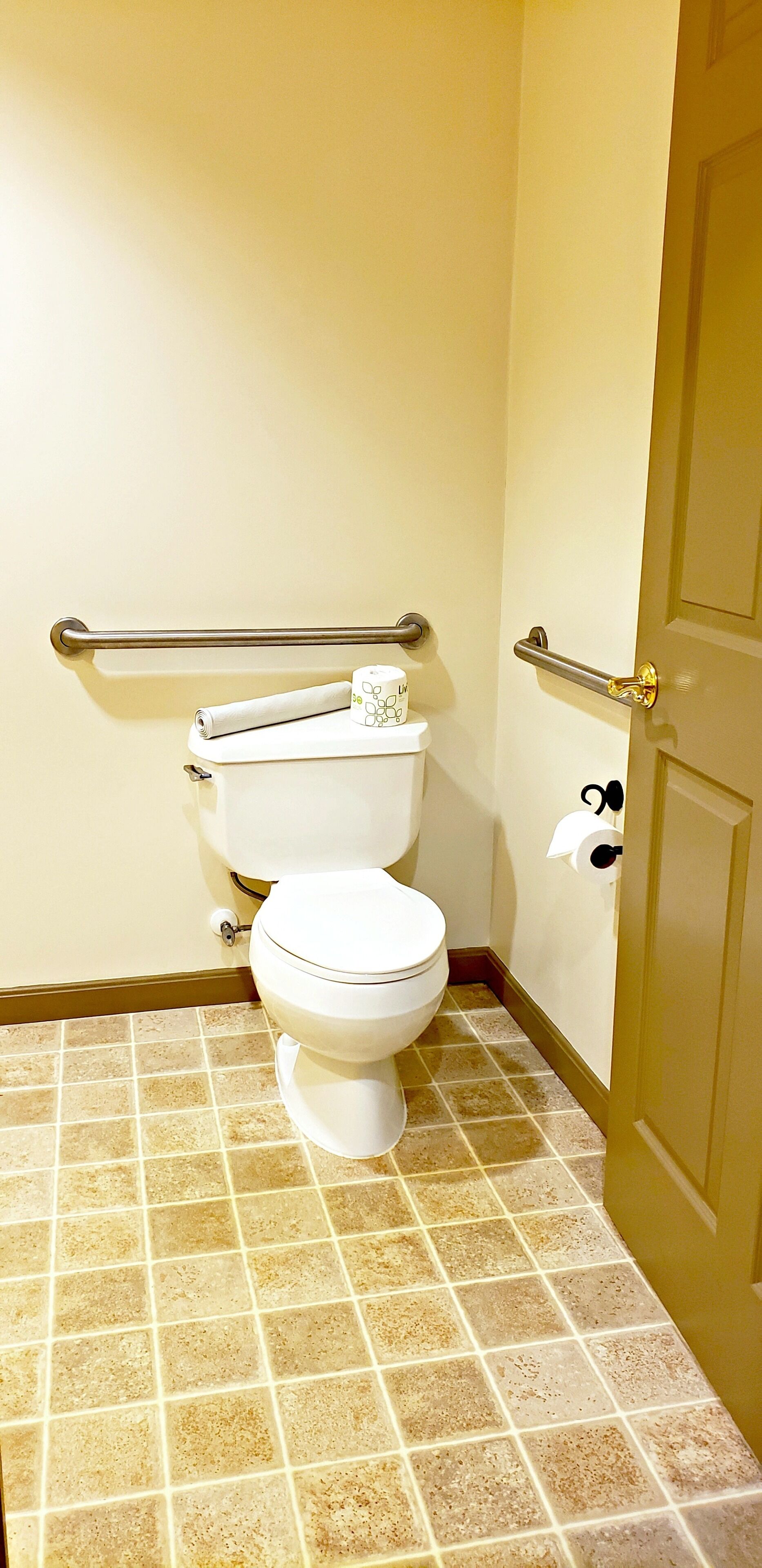 Un baño pequeño con inodoro, barandilla y puerta.