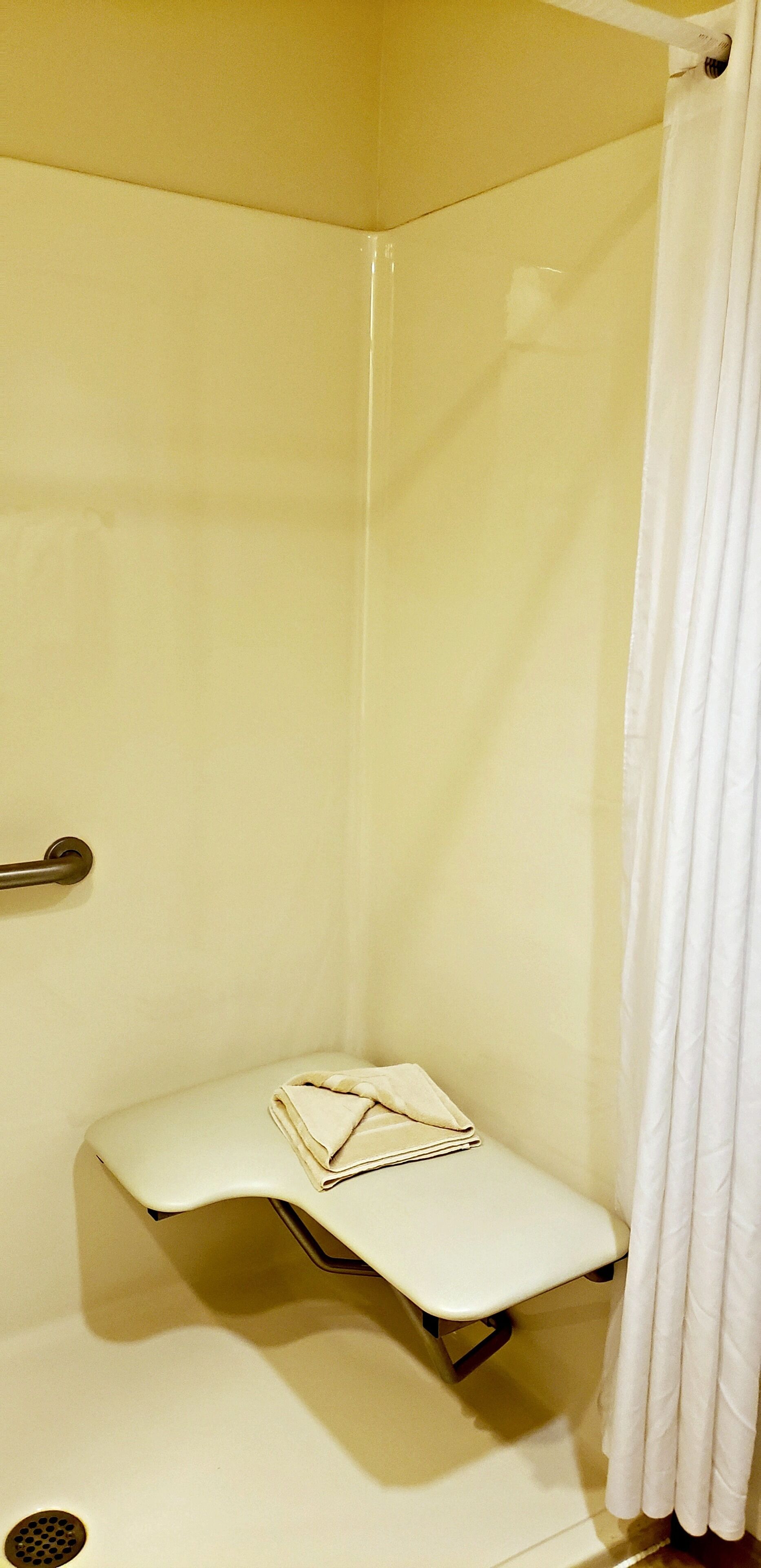 A small, enclosed shower area with a bench and a towel.