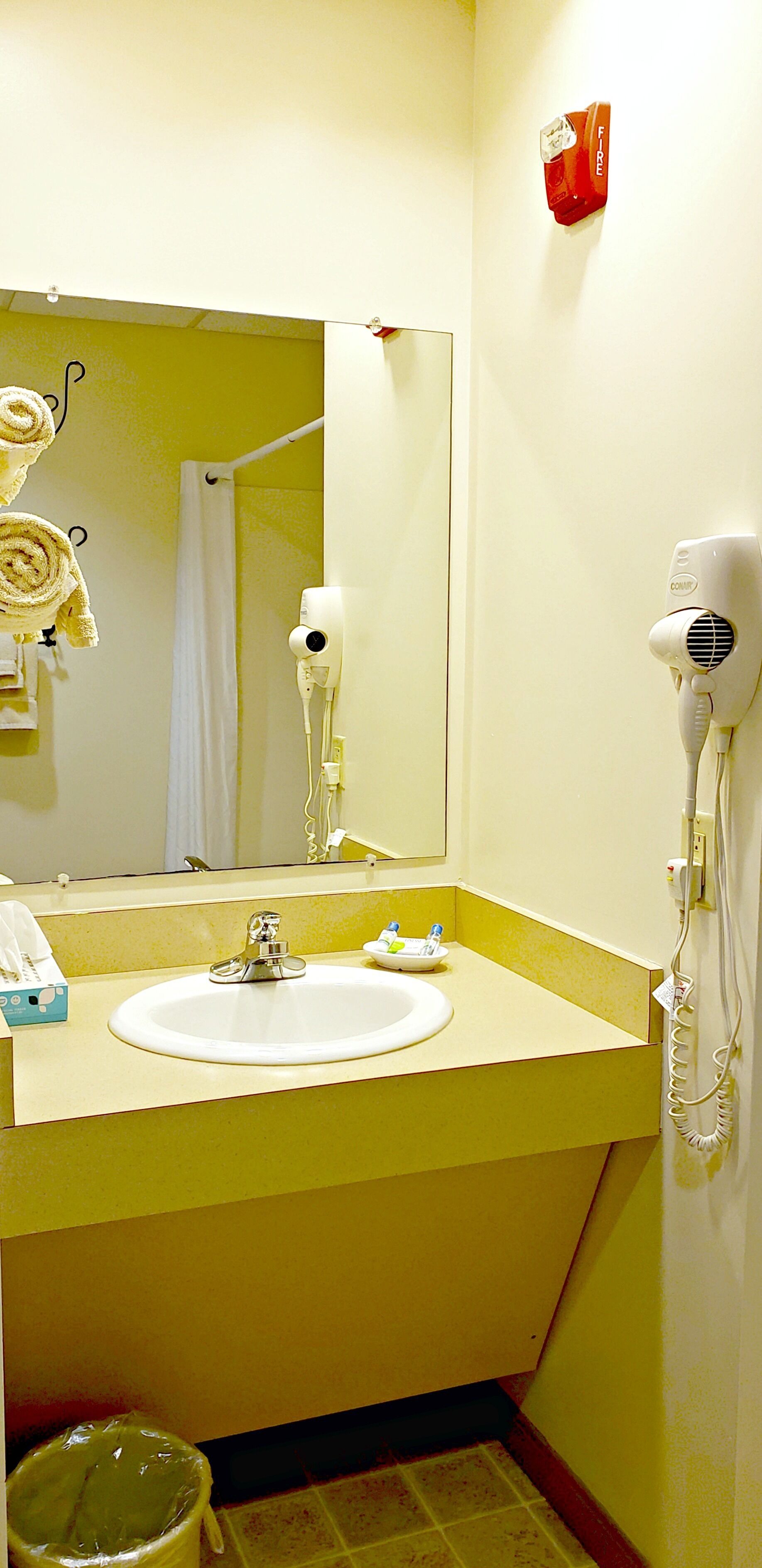 Une salle de bain équipée d’un lavabo, d’un miroir, d’un porte-serviettes et d’un sèche-cheveux.
