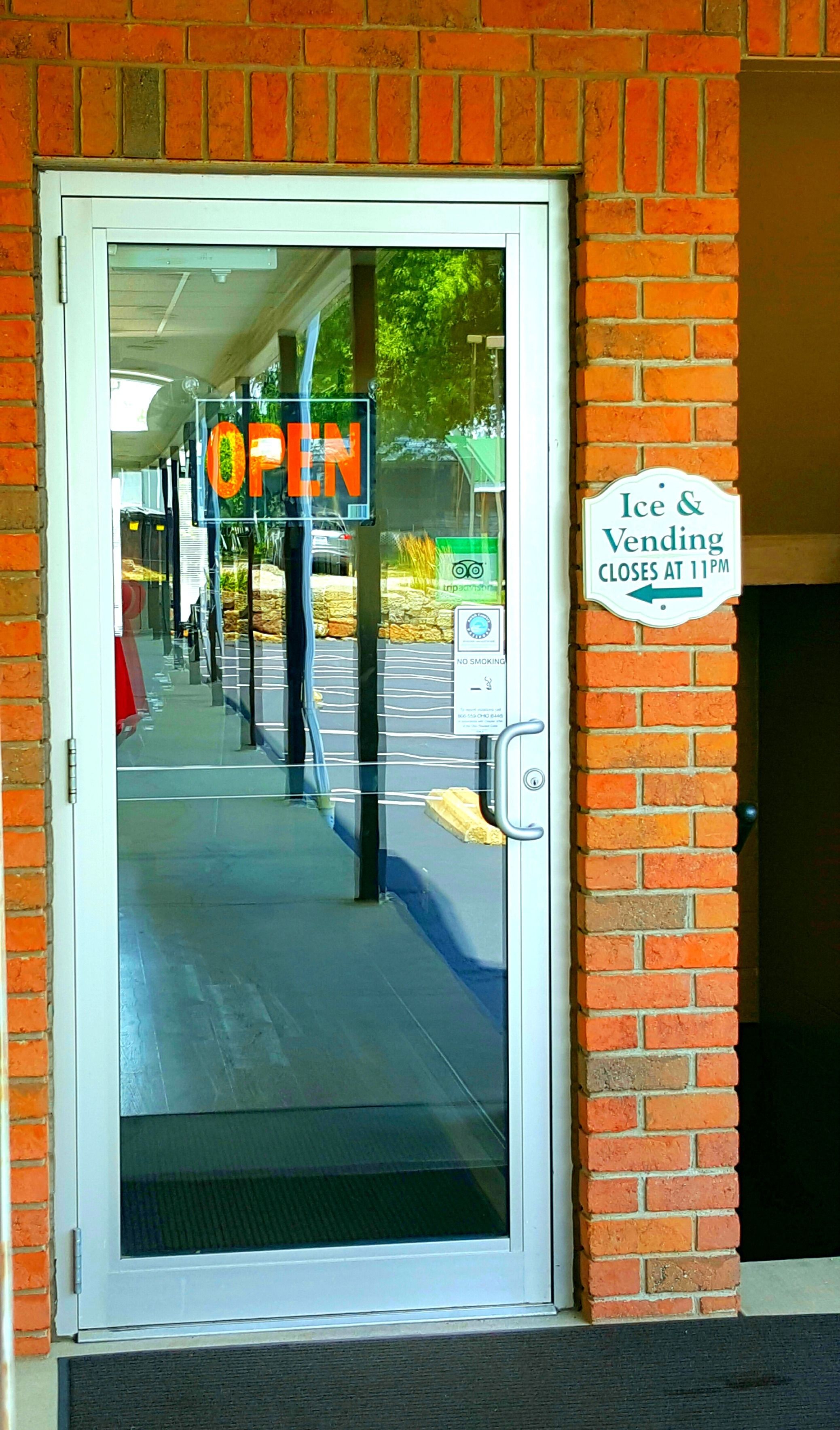 A storefront with a glass door, a sign indicating 'OPEN', and a sign for 'Ice & Vending' with a closing time.