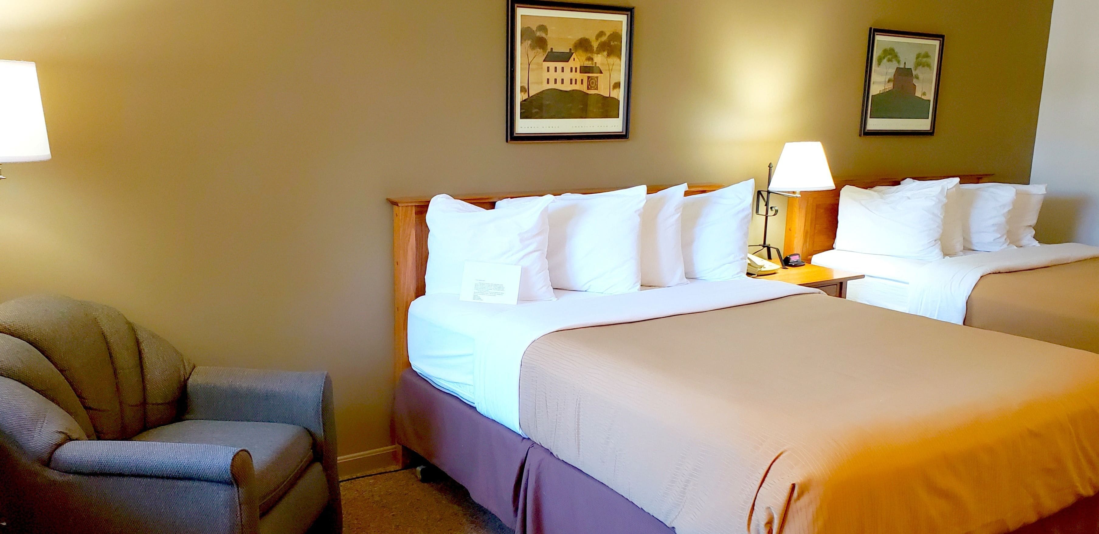 Ein Hotelzimmer mit zwei Betten, einem Sessel und zwei Wandleuchten.