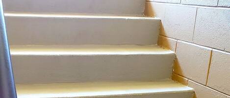 Un conjunto de escalones blancos con barandilla azul, que conducen a un piso superior.