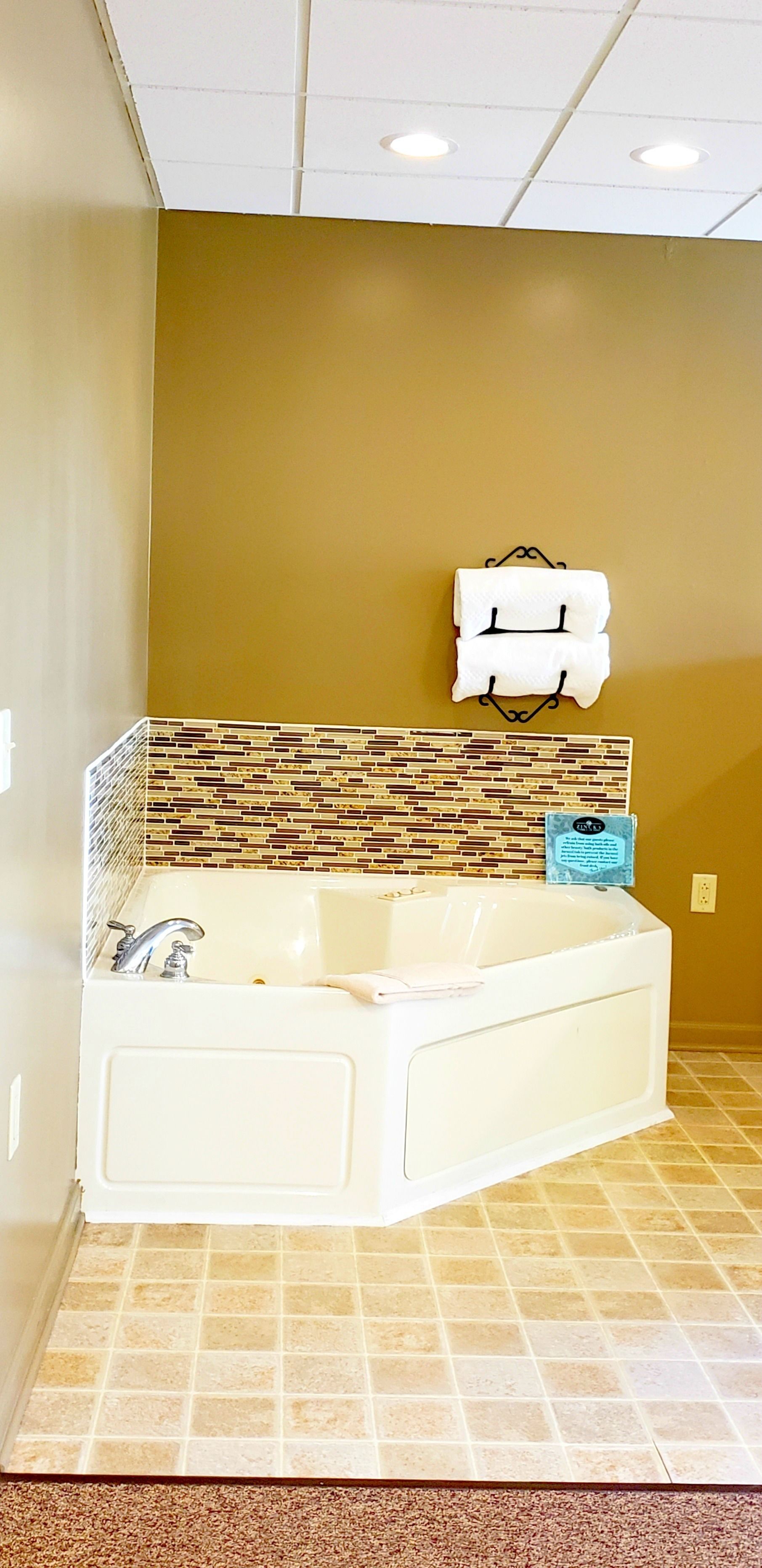 A bathroom with a large bathtub, a tiled floor, and a wall-mounted towel rack.