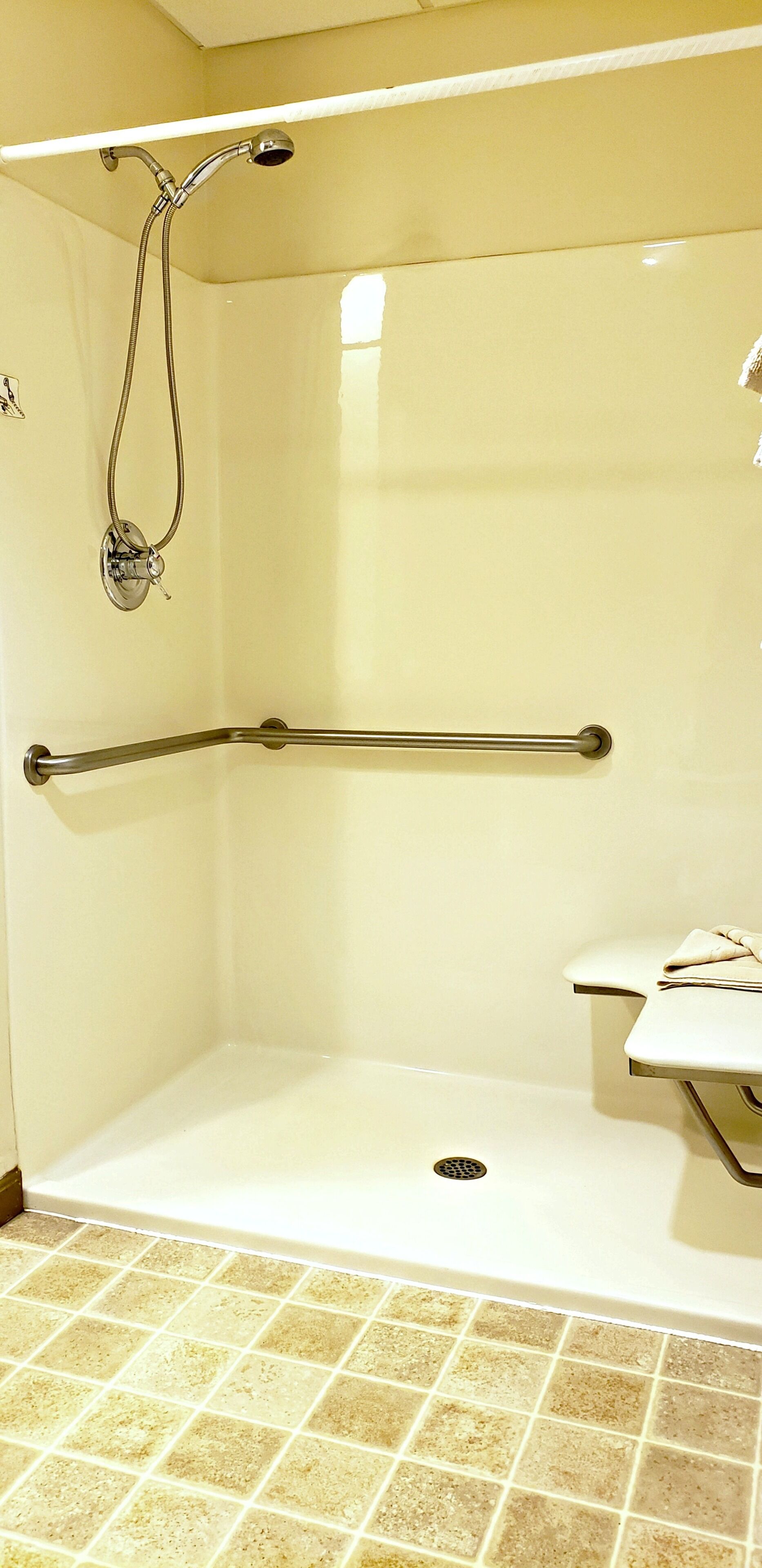 A shower area with a grab bar, a white sink, and a tiled floor.