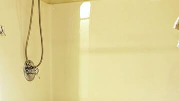 A shower area with a grab bar, a white sink, and a tiled floor.