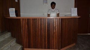 Un mostrador de recepción con listones de madera verticales, un certificado enmarcado en la pared y una puerta a la derecha.