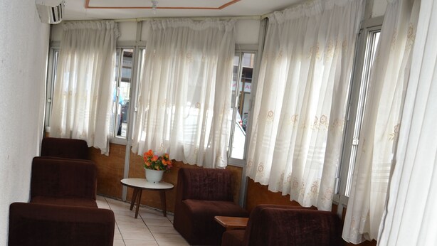 Una habitación con sofás marrones, una mesita redonda pequeña y una ventana con cortinas.