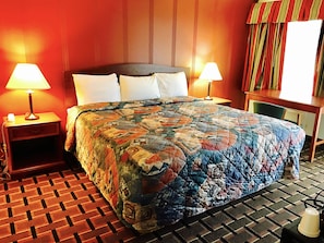 A hotel room with a large bed, two bedside lamps, a patterned carpet, and a window with curtains. - Greystone Motel (Hillsboro)