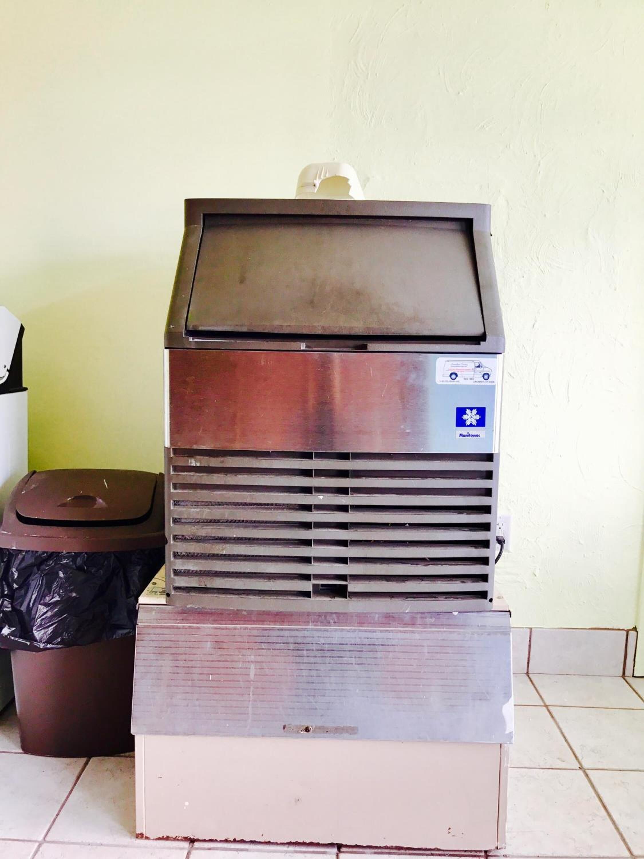 Una máquina expendedora con ranura para monedas, una pantalla de visualización y un cesto de basura cerca.