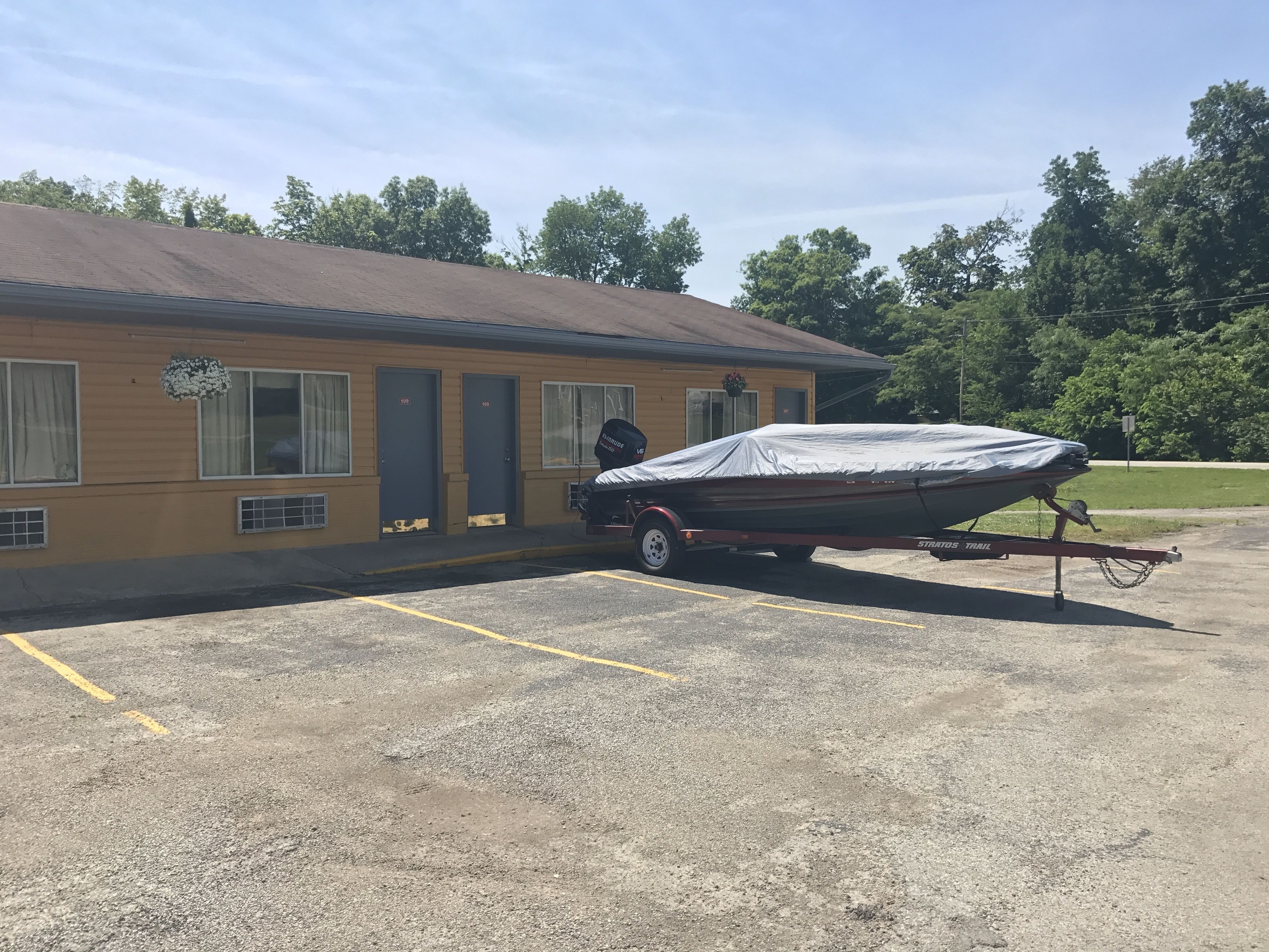 Un motel avec un bateau couvert, posé sur une remorque, dans le parking.