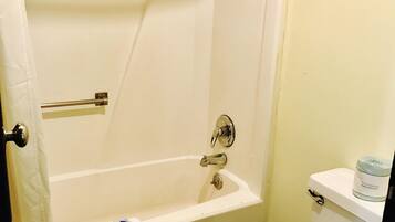 A bathroom with a bathtub, toilet, and a towel rack.