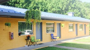 A yellow building with a blue roof, large windows, and hanging plants. - Greystone Motel (Hillsboro)