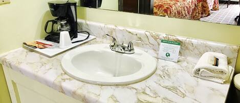 A bathroom with a marble sink, a coffee maker, a towel, and a 'Save Our Planet' sign.