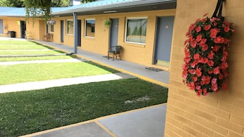 A motel with a yellow exterior, a covered walkway, and a hanging flower basket.