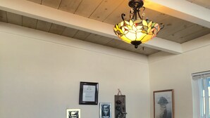 Ein gemütliches Zimmer mit Holzbalkendecke, einer dekorativen Leuchte, einem an der Wand befestigten Regal mit Postkarten und einer Buddha-Statue.