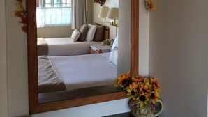 Ein Schlafzimmer mit einem großen Spiegel, floralen Dekorationen und einem Nachttisch mit einer Vase.