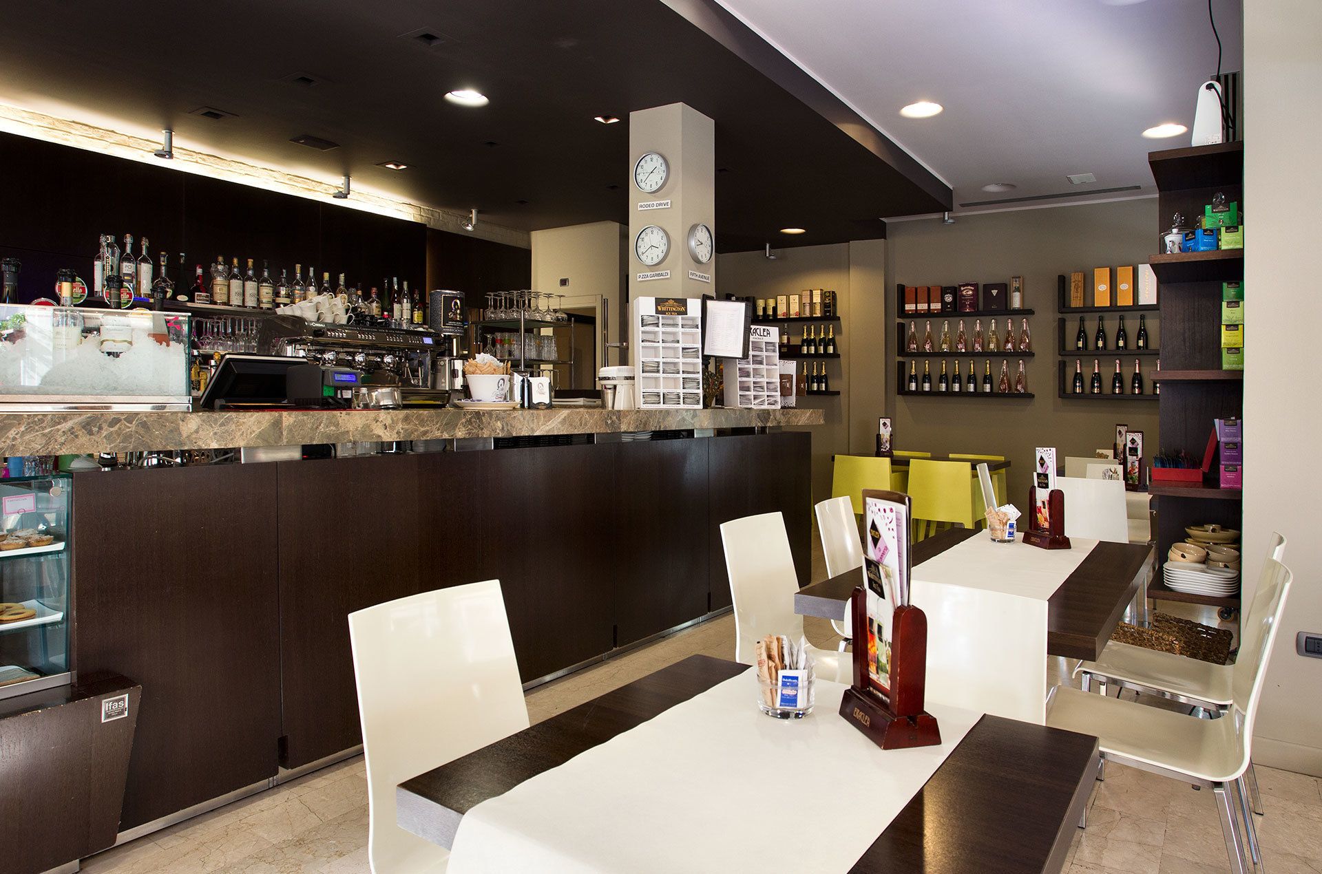 A modern bar area with a counter, seating, and a wine display.