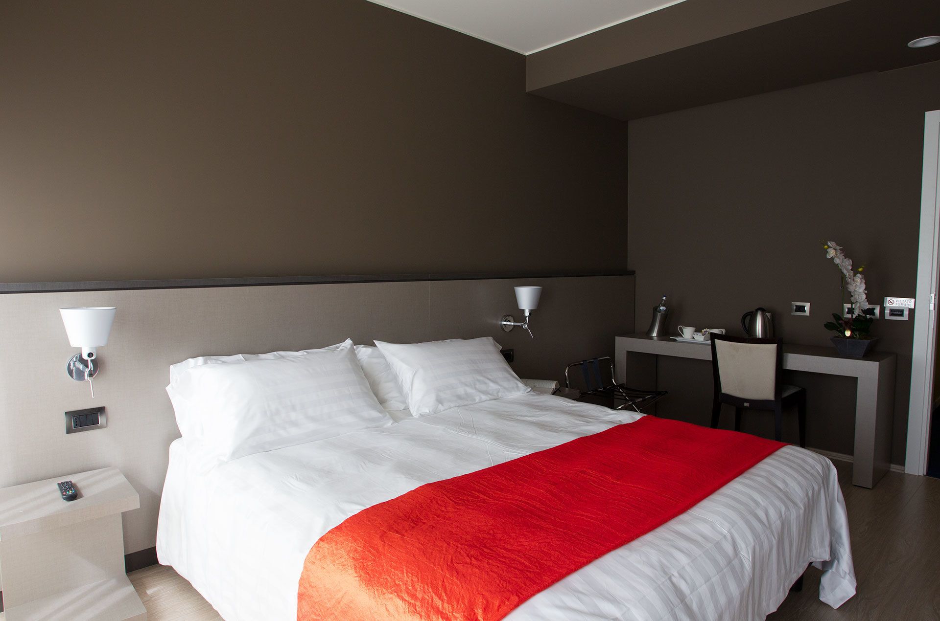 Een hotelkamer met een bed, nachtkastjes, een bureau en een stoel.