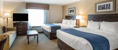 A hotel room with two beds, a TV, a desk, and a chair.