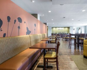A restaurant with booths and tables, a counter with a menu, and a wall with floral designs. - MainStay Suites Cartersville - Emerson Lake Point (Cartersville)
