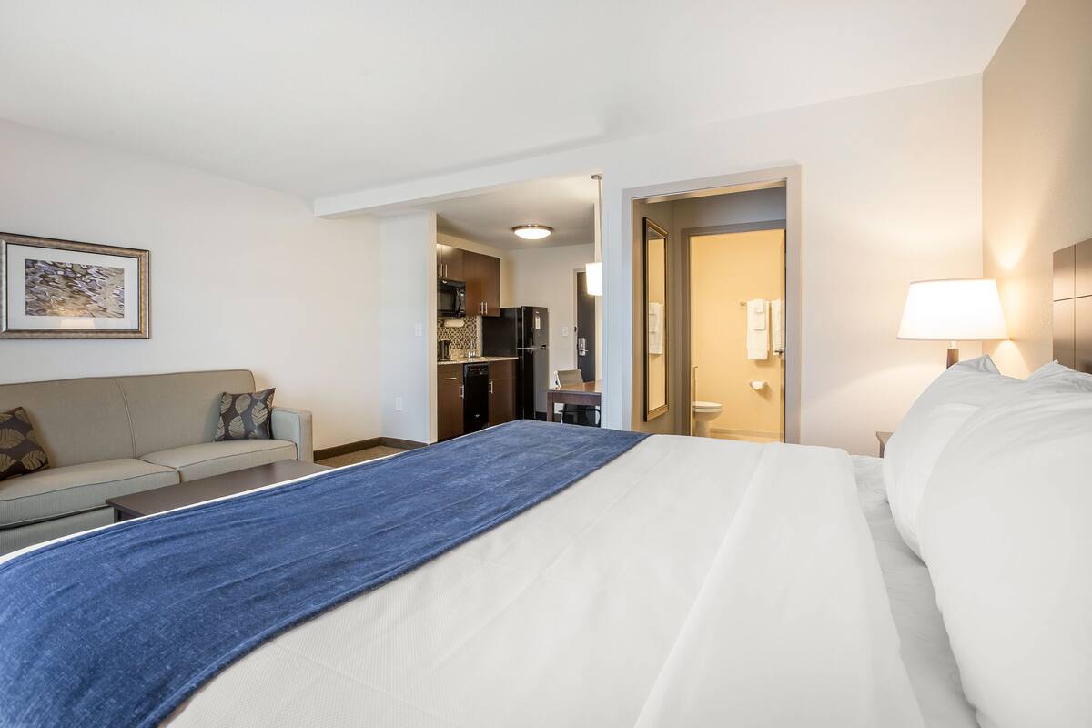 Een hotelkamer met een bed, een slaapbank, een bureau en een kitchenette.