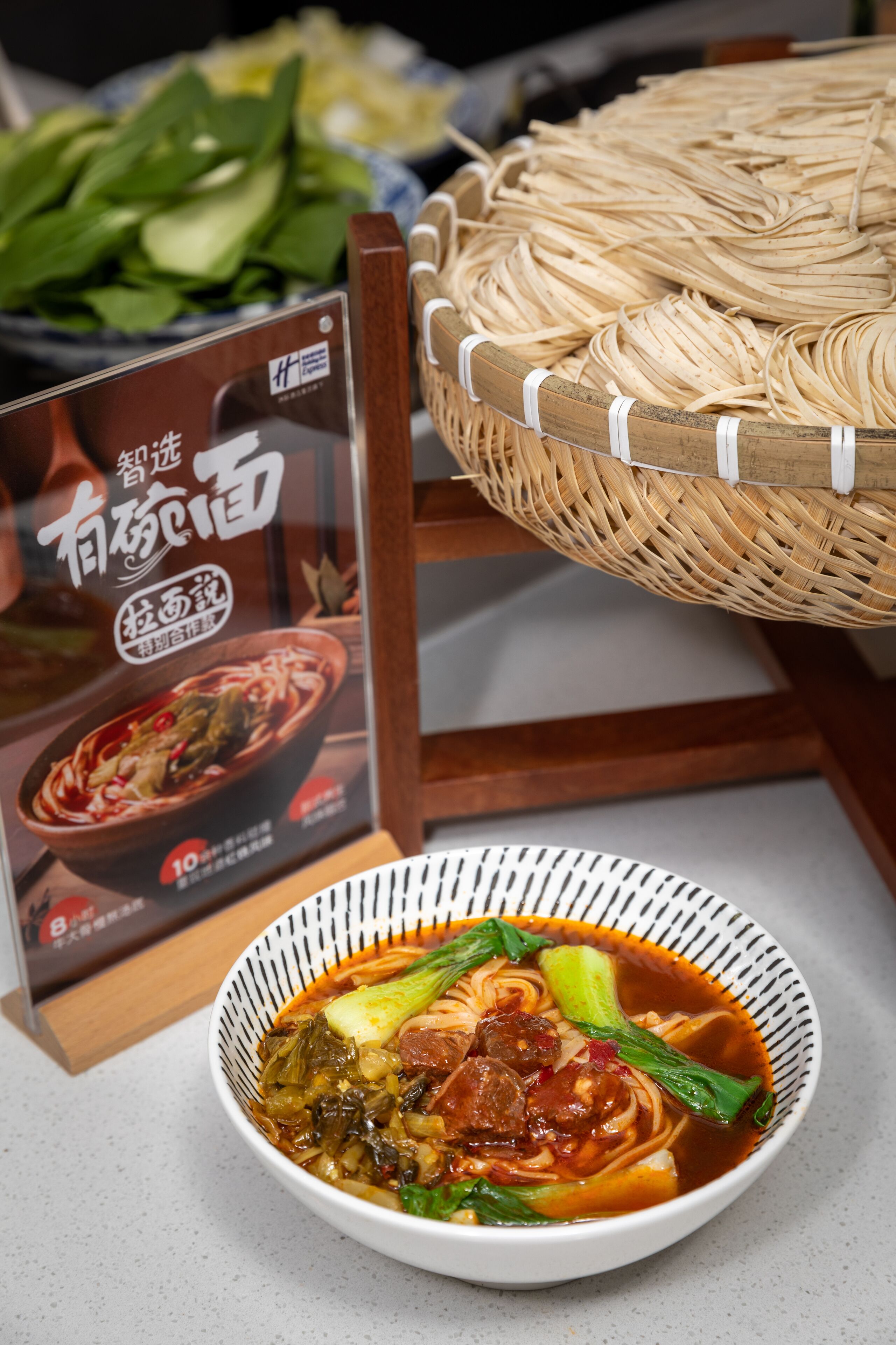 A bowl of soup with vegetables and meat, a wicker basket with noodles, and a menu sign.