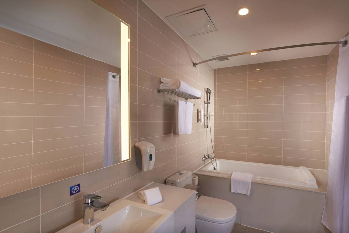 A modern bathroom with a sink, toilet, and bathtub.