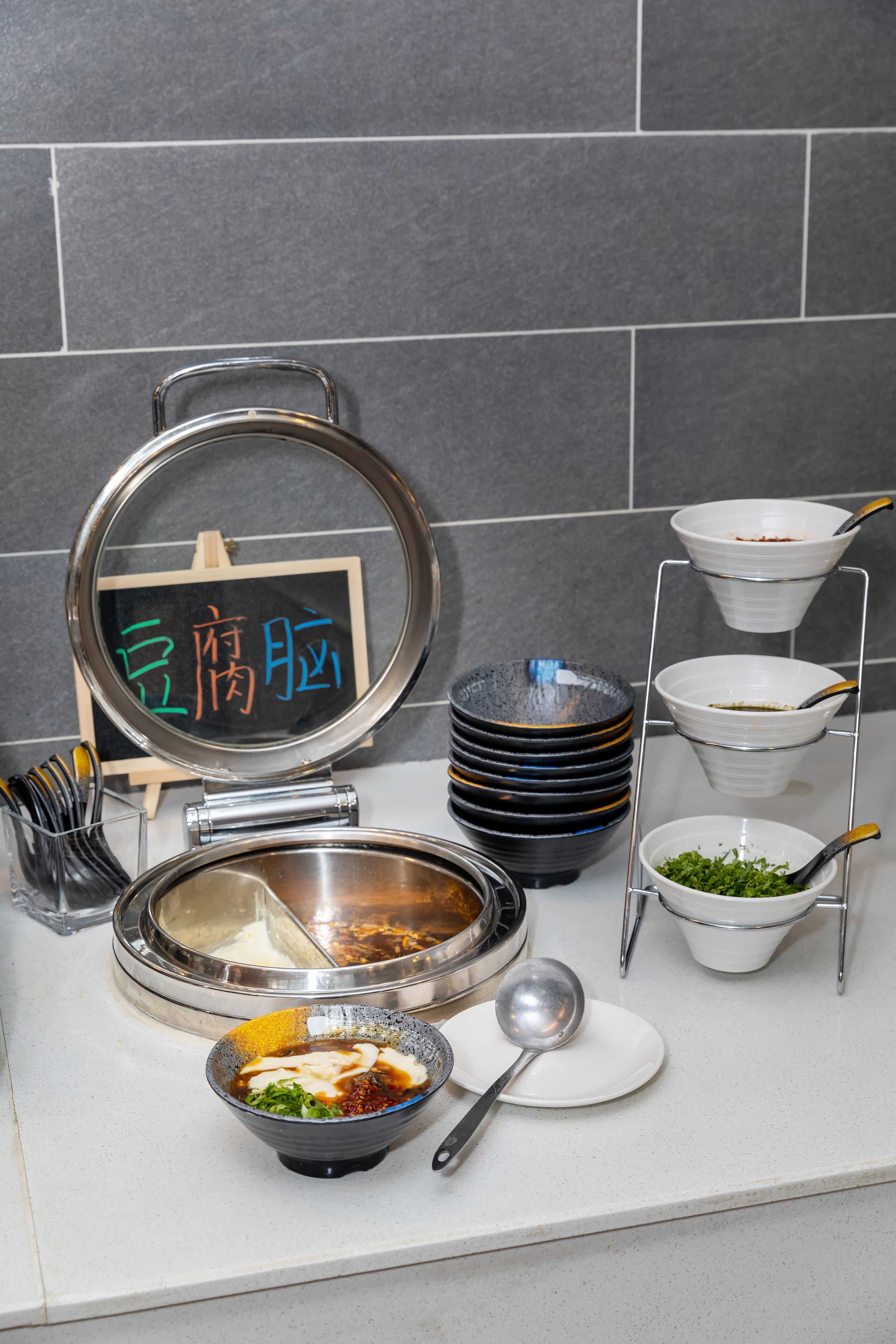 Una encimera de cocina con varios cuencos, una cuchara grande y una pila de platos.
