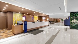 A modern hotel reception area with a wooden reception desk, a digital screen, and a wall-mounted sign. - Holiday Inn Express Shenyang North Station by IHG (Shenyang)