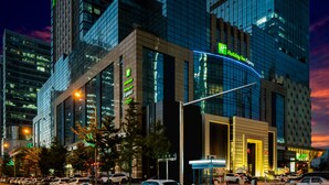 Un hotel Holiday Inn Express con fachada de vidrio moderna, situado en un paisaje urbano al atardecer.
